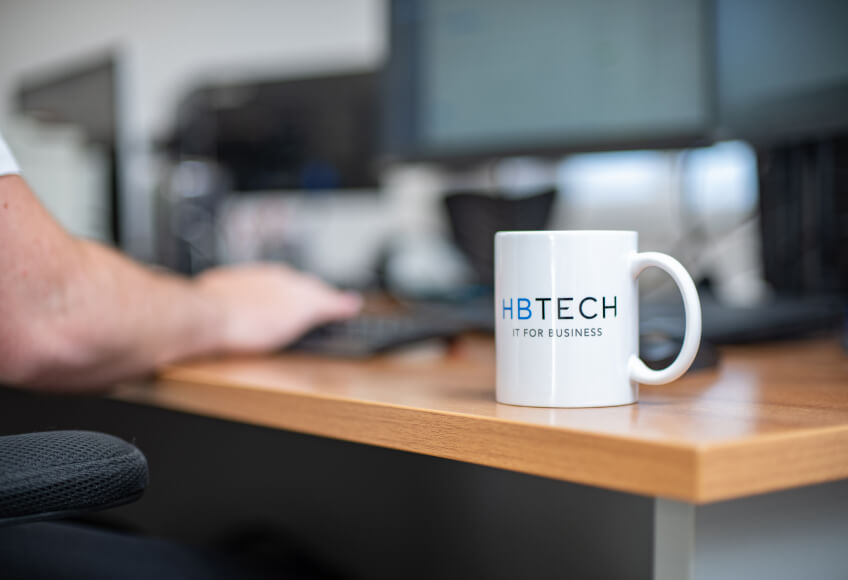 Photo of a HB Tech mug on the desk of an IT technician.